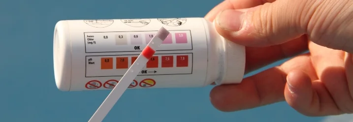 Person hält Teststreifen für Poolwasser